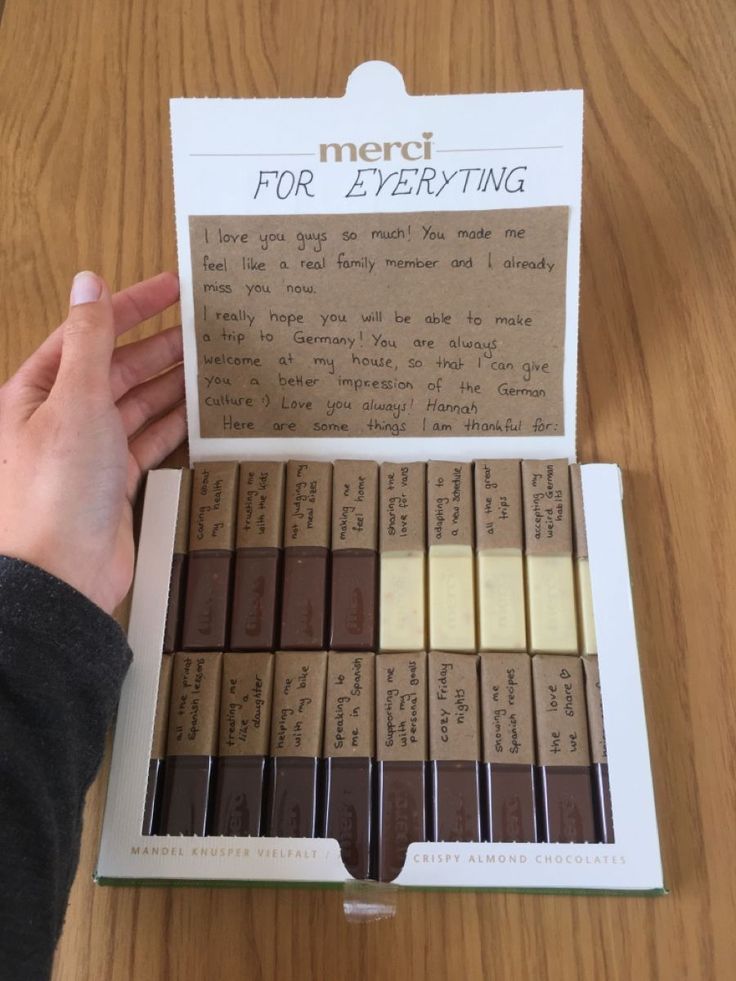 a person holding a box of chocolates on a table with the words merci for everything written in it