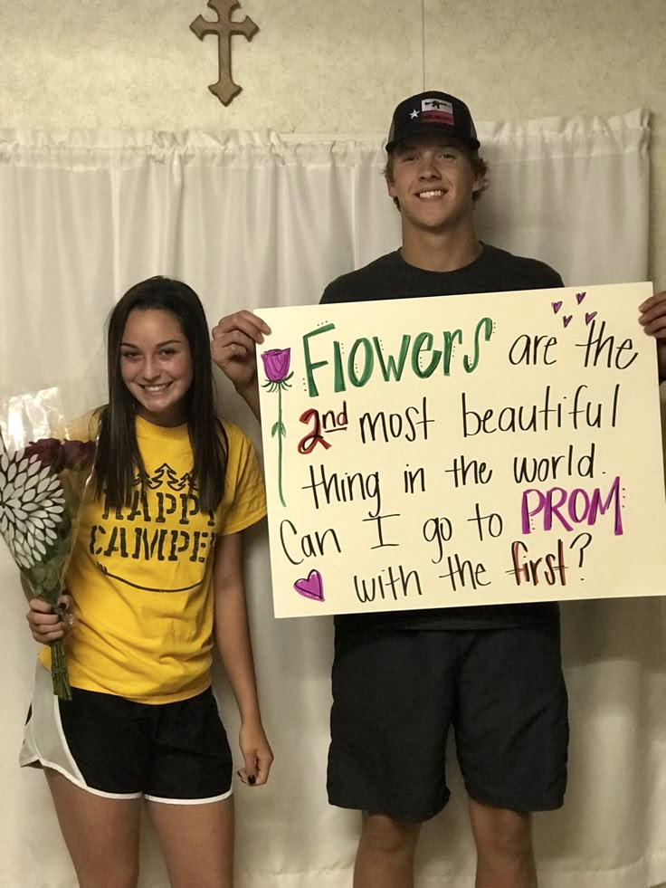 two people standing next to each other holding flowers and a sign that says flowers are the most beautiful thing in the world