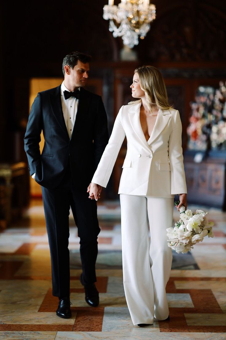 a man and woman in formal wear holding hands