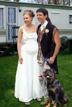 a man and woman standing next to a dog in front of a mobile home with a trailer behind them