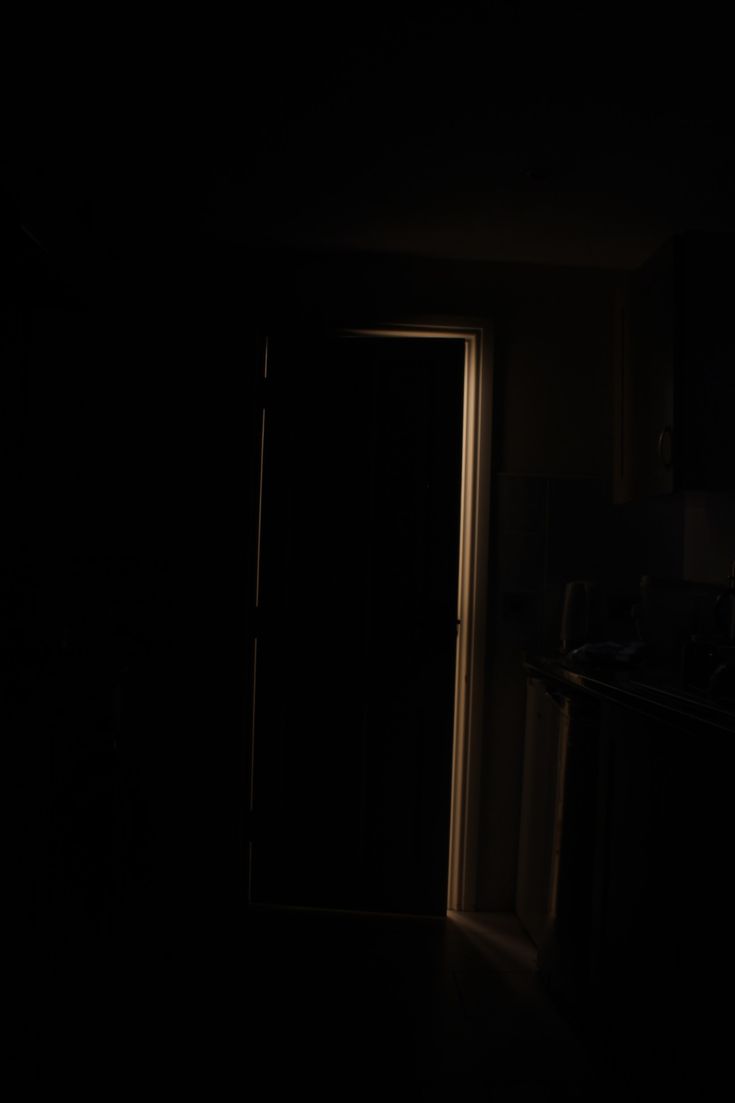 an open door in a dark room with the light shining on it's side