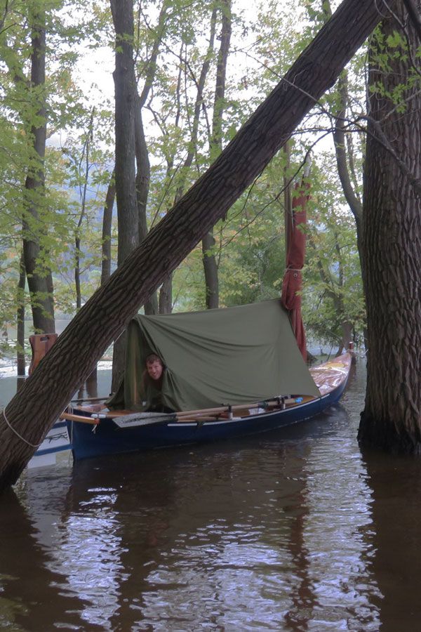 a boat with a tarp on it is in the middle of water near trees