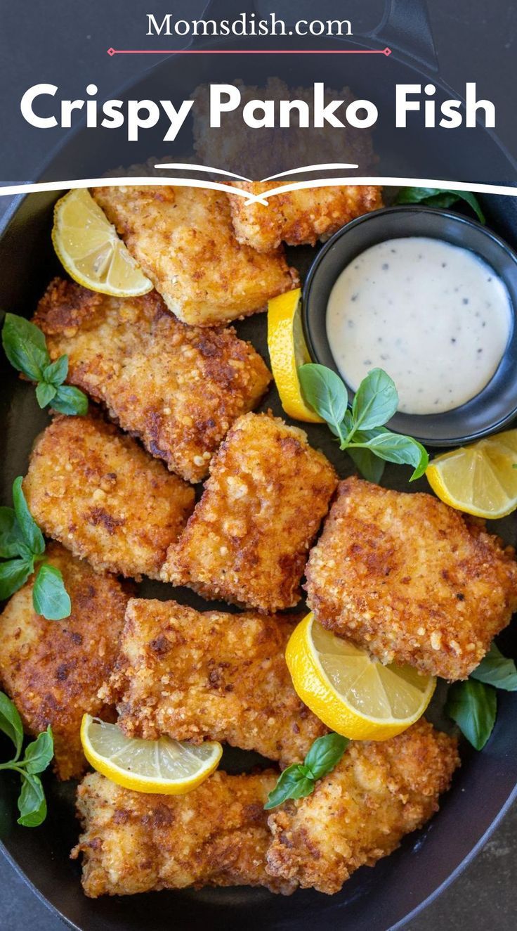 crispy panko fish in a skillet with lemon wedges and ranch dressing