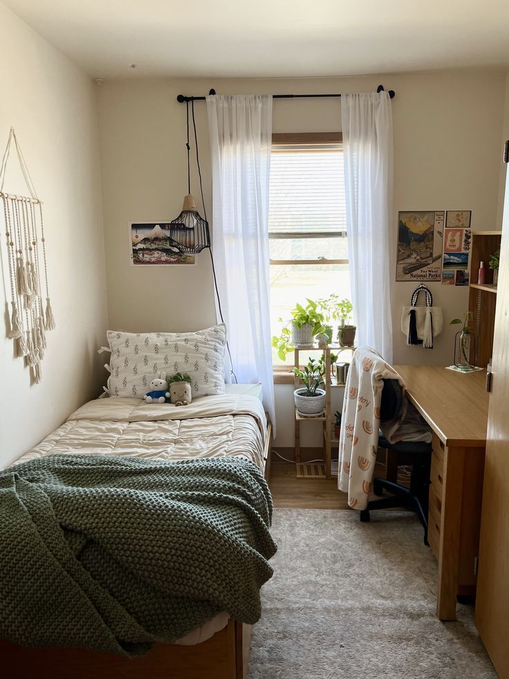 a small bedroom with a bed, desk and window in it's center area