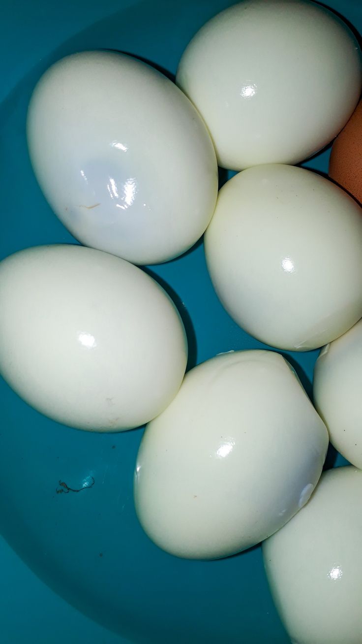 several eggs are in a blue bowl on the table