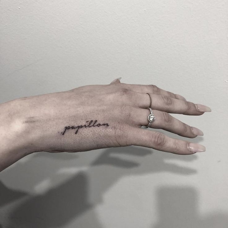 a woman's left hand with a small tattoo on the middle finger that says fragile