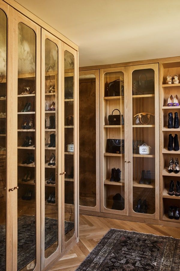 a large wooden closet filled with lots of purses and handbags on shelves next to a rug