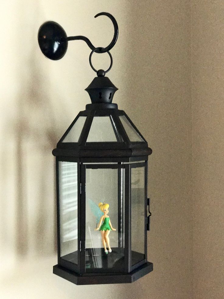 a lamp hanging from the side of a wall with a doll in front of it