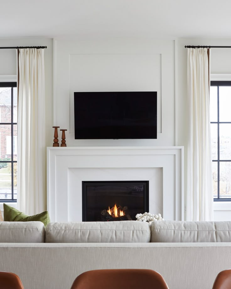 a living room filled with furniture and a flat screen tv mounted above a fire place