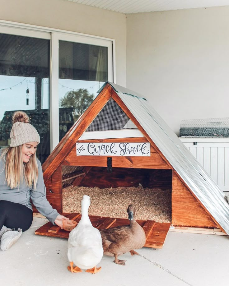 a woman kneeling down next to two geese in a coop house with the words, the grace street written on it