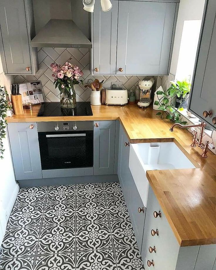 a kitchen with grey cabinets and wooden counter tops, white appliances and flowers in vases