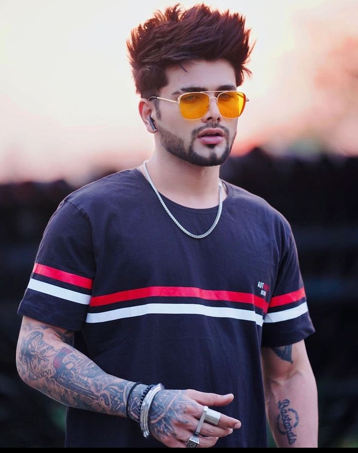 a man with tattoos and yellow sunglasses talking to someone