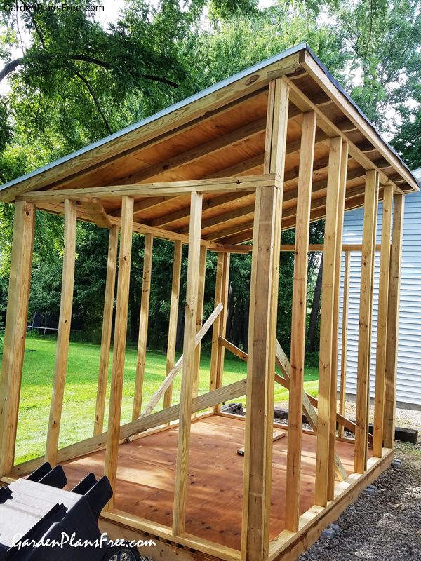 a small wooden structure sitting in the middle of a yard with lots of wood on it