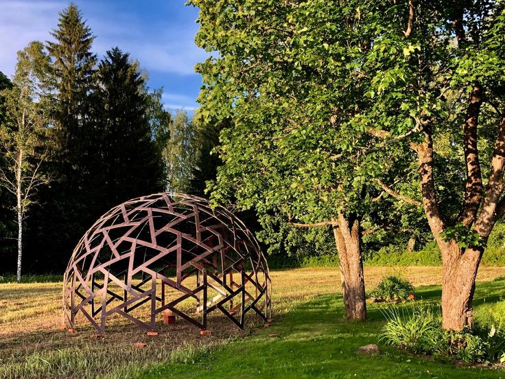 a large metal structure sitting in the middle of a field next to trees and grass