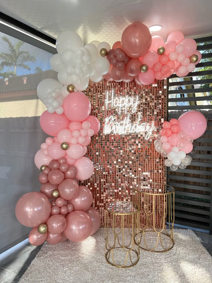 there is a large balloon arch with pink, white and gold balloons on top of it