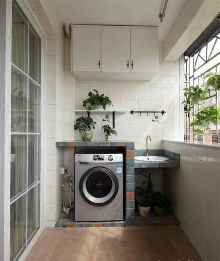 a washer and dryer in a small room next to a window with potted plants