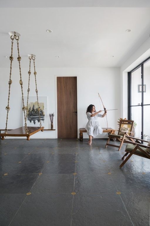 a woman in a white dress is holding a bow and arrow while looking out the window