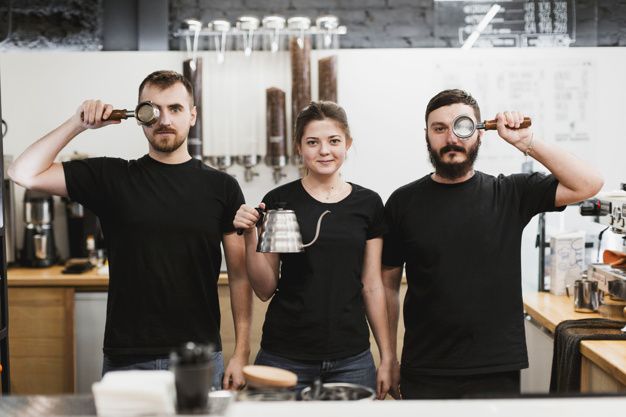 three people standing in front of a coffee machine with their hands on the cups and looking at the camera