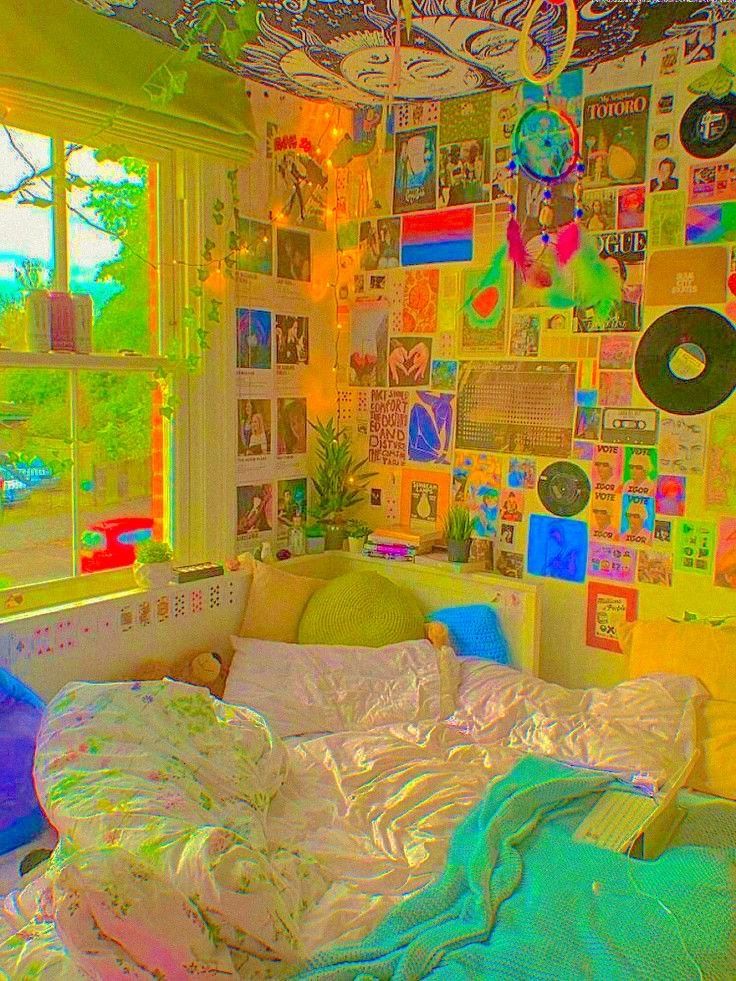 a bed sitting under a window next to a wall covered in pictures and posters on it