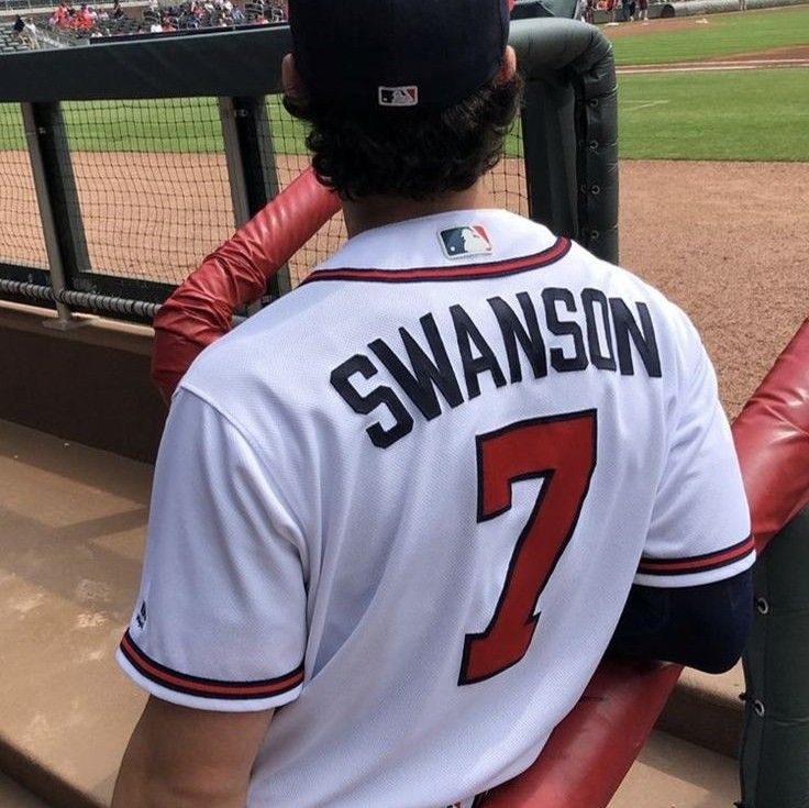 a baseball player sitting in the dugout at a game