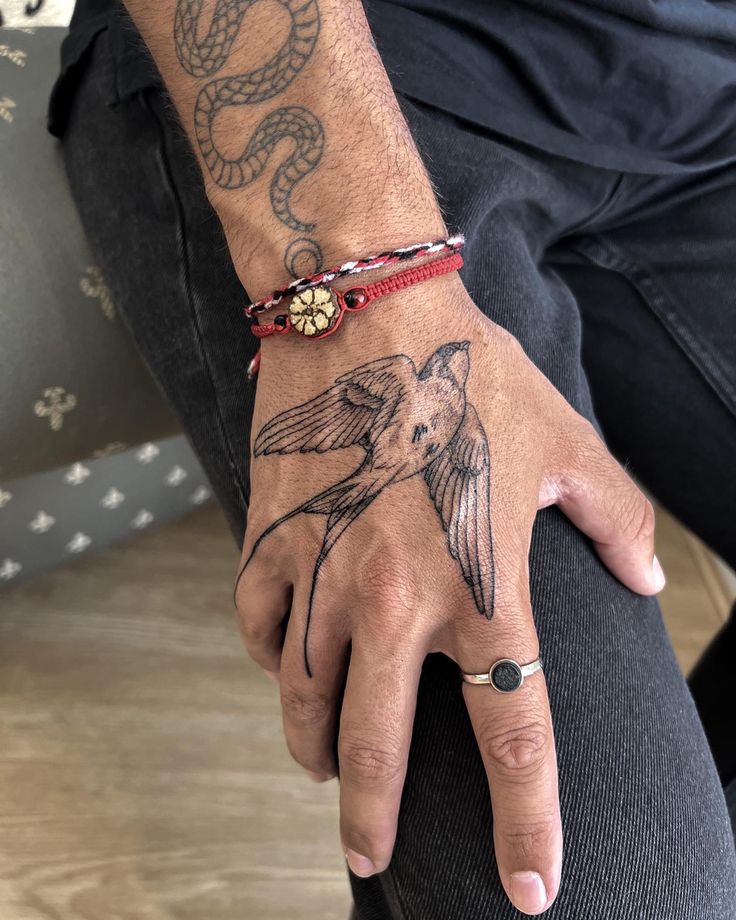 a man with a tattoo on his arm and hand is wearing a red beaded bracelet