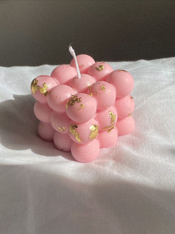 a bunch of pink balls with gold sprinkles on them sitting on a white sheet