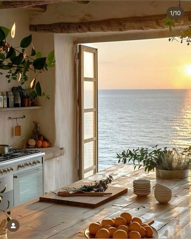 a kitchen with an open door leading to the ocean and oranges on a cutting board