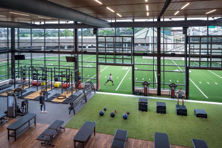 the inside of a gym with people exercising on treadmills and exercise equipment in front of large windows