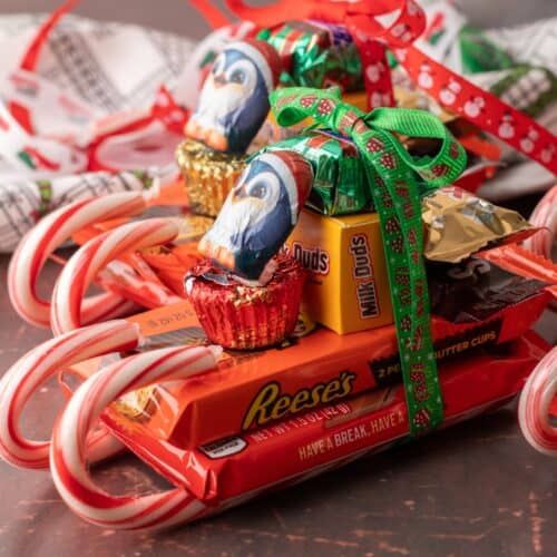 an assortment of candy and candies in a cart with ribbons on the top, sitting on a table