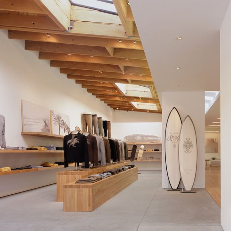 a surfboard is on display in a store with wooden beams and skylights above it