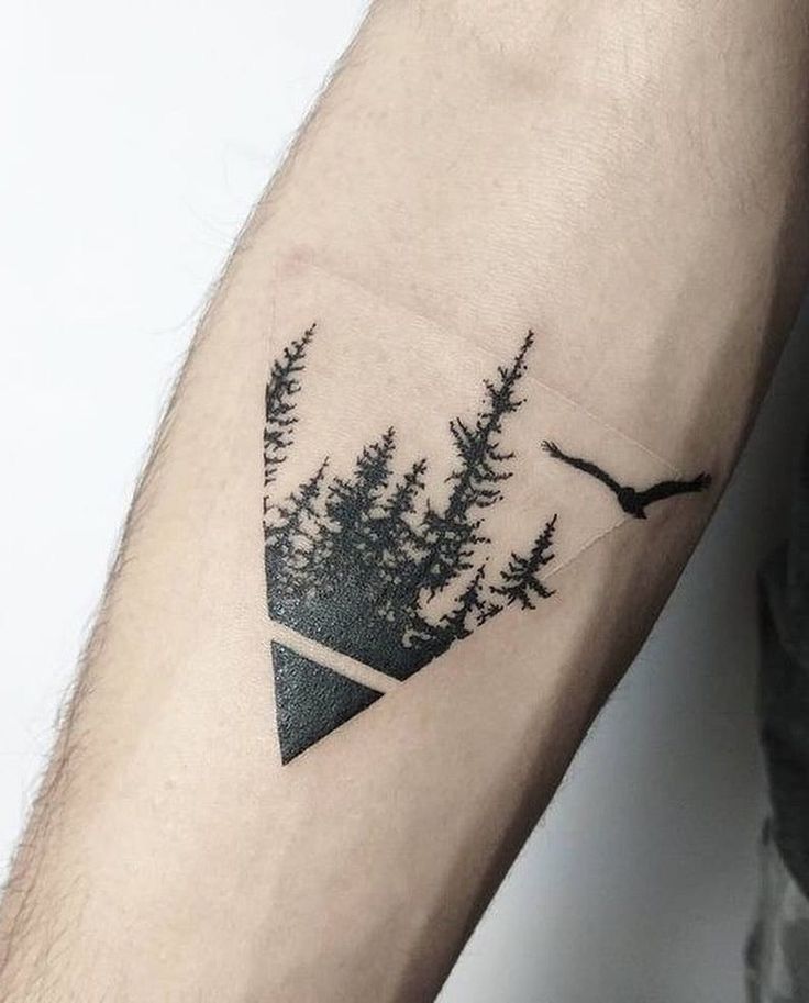 a man's arm with trees and an eagle tattoo on the left side of his arm