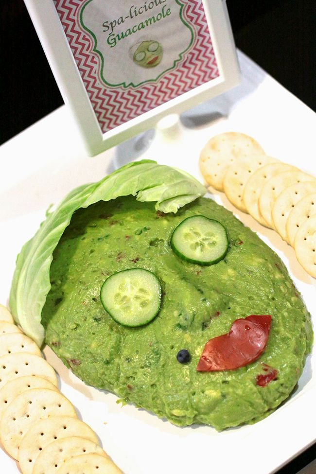 a green face made out of lettuce and cucumbers on a plate with crackers