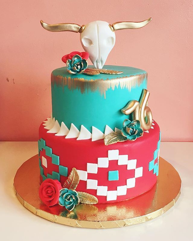 a colorful cake decorated with flowers and an animal's head on top is sitting on a gold platter