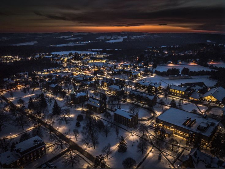 an aerial view of a city at night with lights on and snow covering the ground