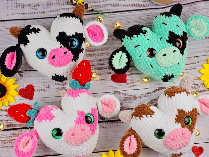 crocheted stuffed animals with hearts and sunflowers on wooden table next to each other