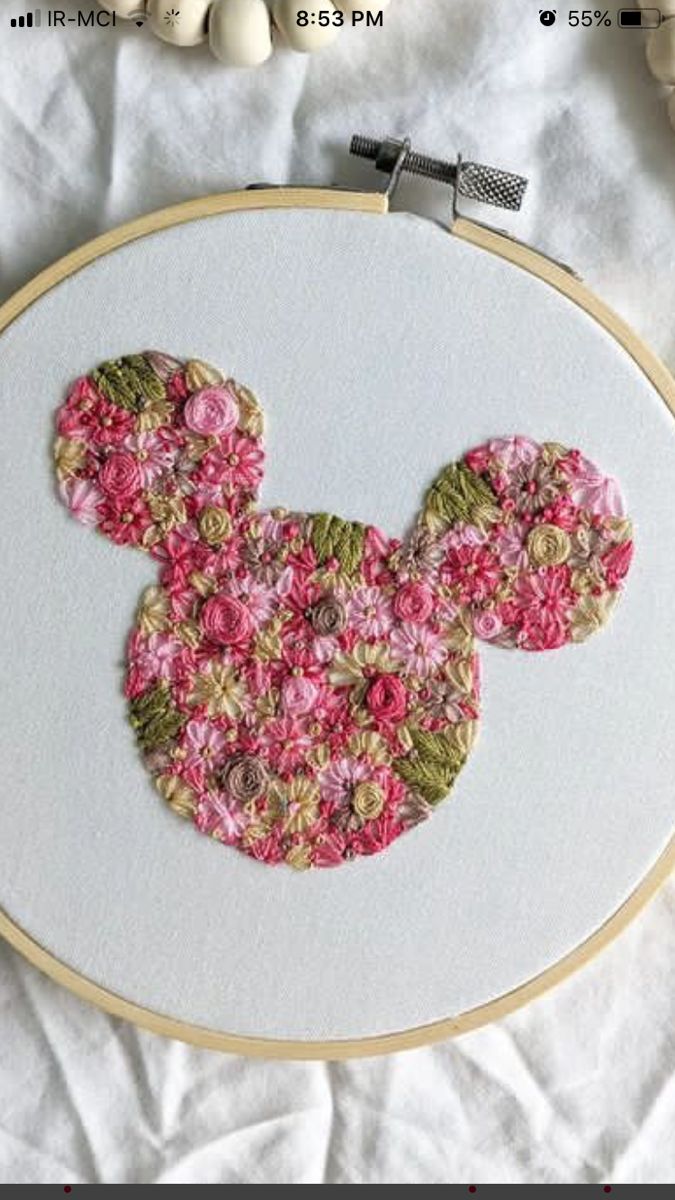 a close up of a cross stitch mouse face on a white surface with other items in the background