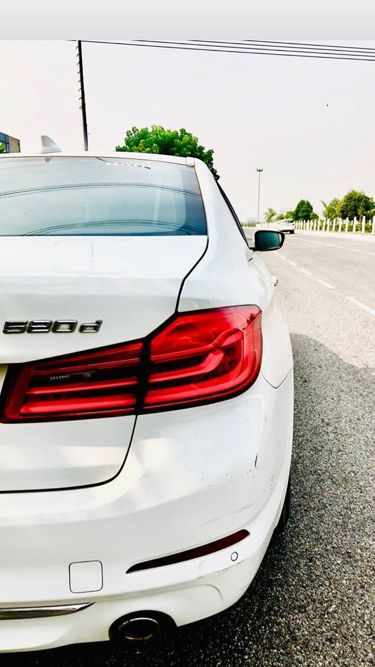 the back end of a white car parked in a parking lot