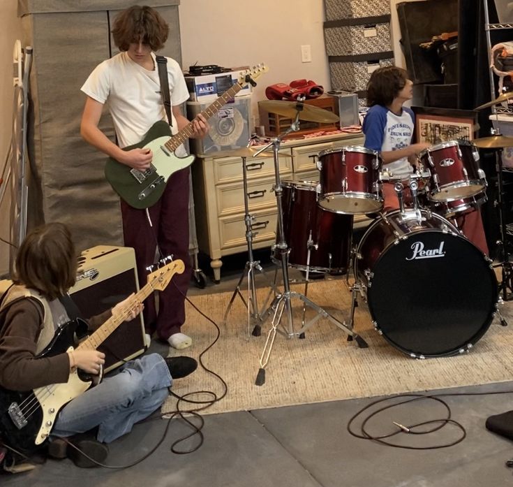 a group of young people playing instruments in a music studio with guitars and drum sticks