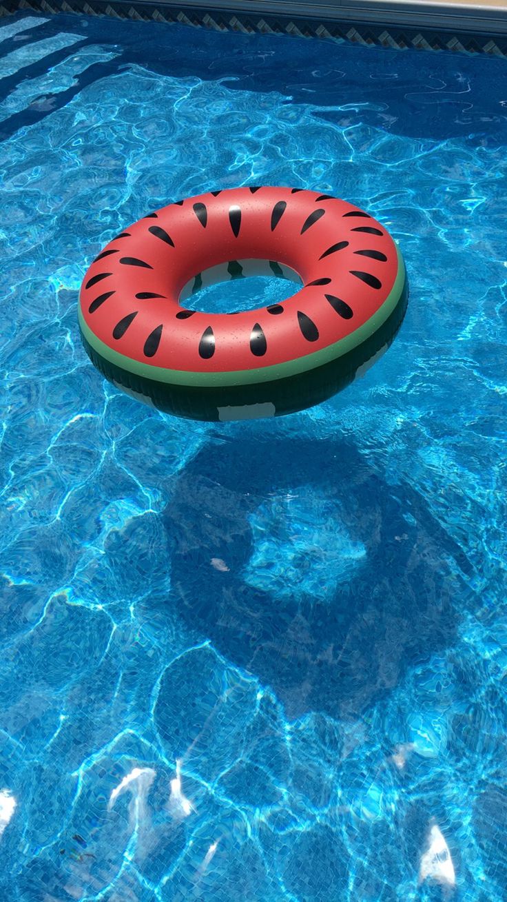 an inflatable ring floating on the side of a swimming pool with blue water