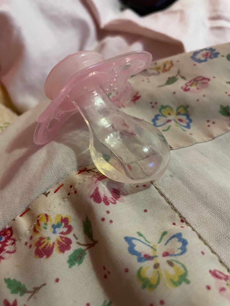 a pink pacifier sitting on top of a bed