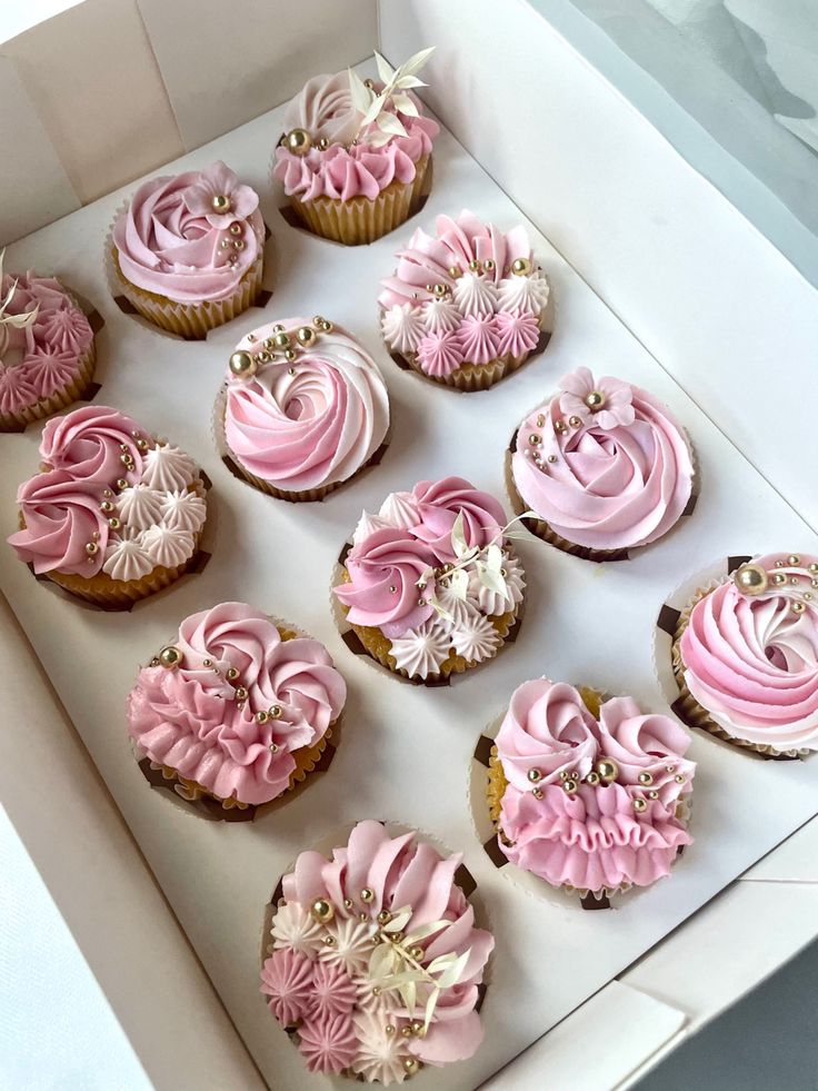 twelve cupcakes with pink frosting in a box