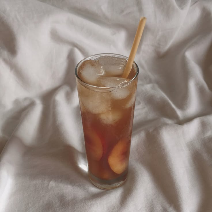 a glass filled with ice and fruit on top of a white cloth covered tablecloth