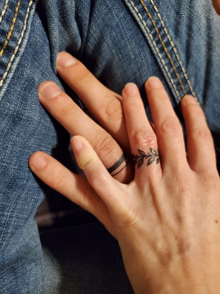 a woman's hand with a ring on it and an arrow tattoo on her finger