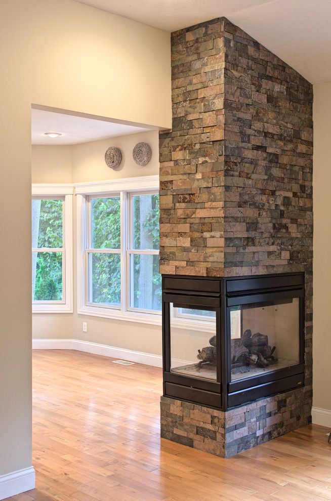 an empty living room with wood floors and a brick fireplace in the middle of it