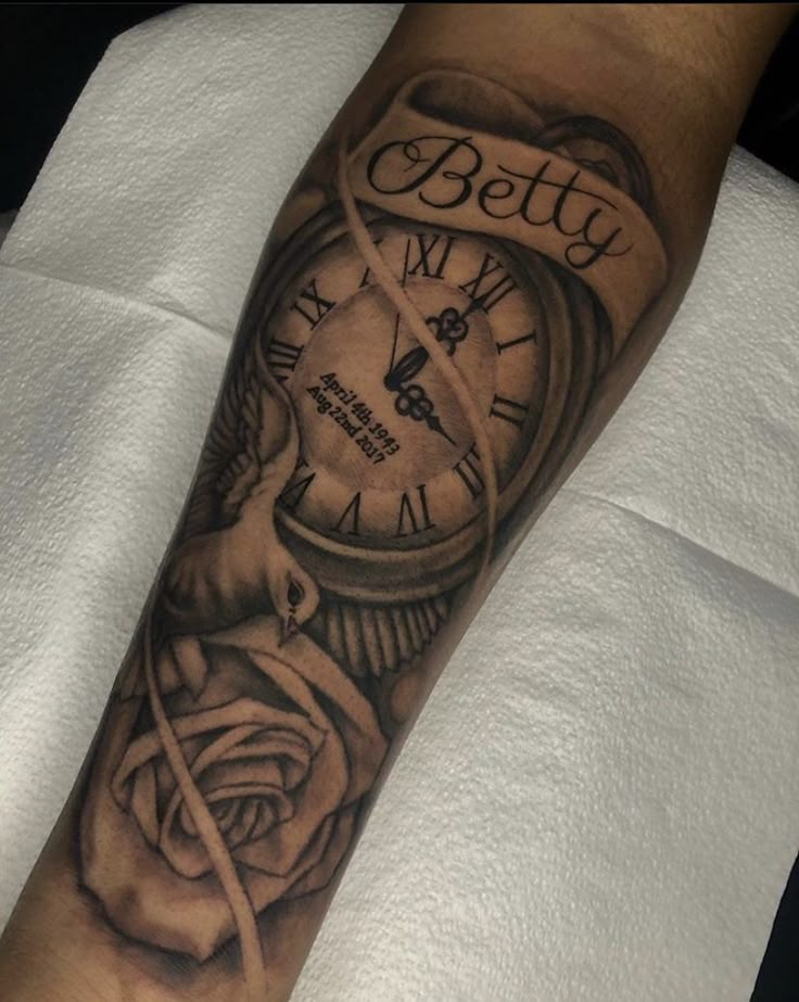 a man's arm with a clock and rose tattoo on it, which reads betty