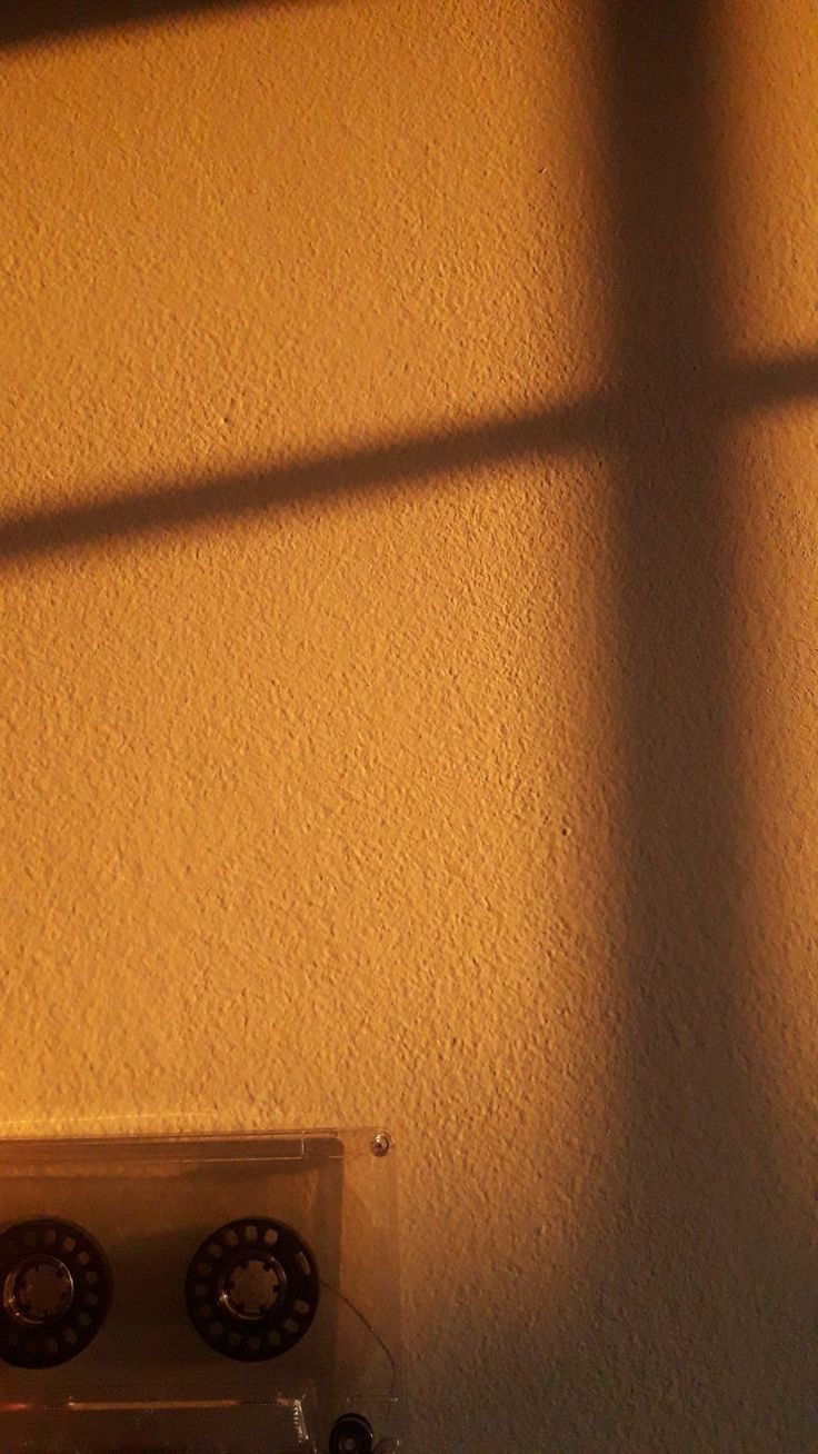 a stove top oven sitting under a window next to a white wall with the light coming through it