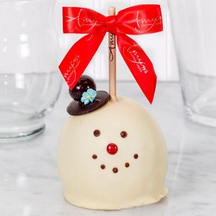 a white cake topped with a red bow and a frosted snowman on top