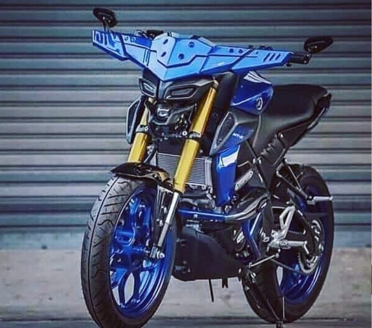 a blue and black motorcycle parked in front of a garage door