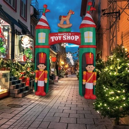 an inflatable toy shop entrance with christmas trees and lights on the side walk