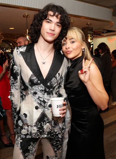 two people standing next to each other holding coffee cups and posing for the camera at an event